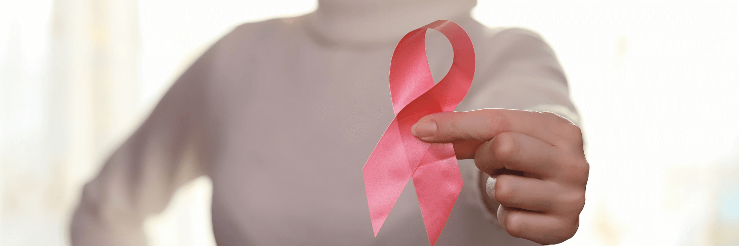 A woman holding a pink breast cancer awareness ribbon with her left hand